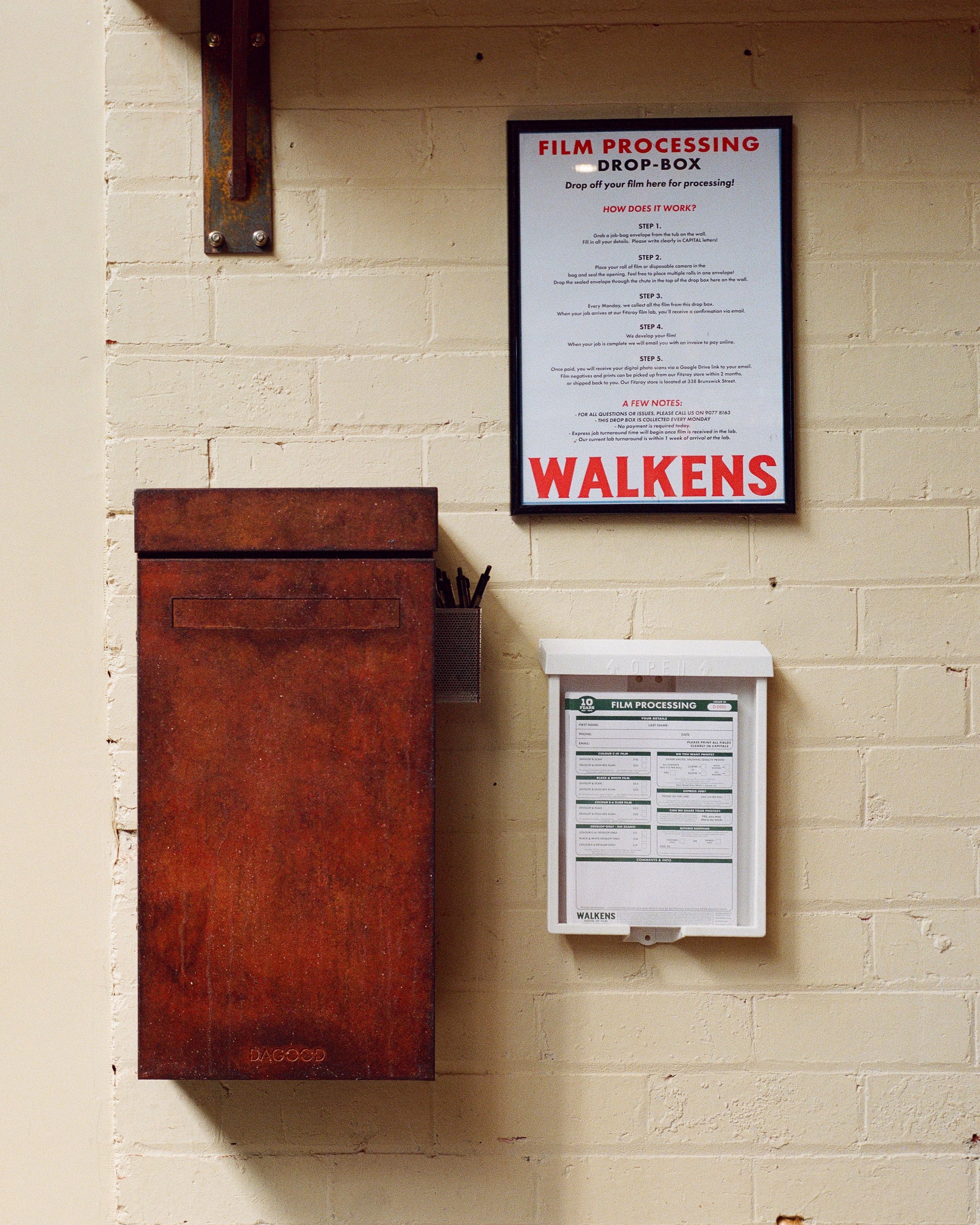 Dropbox and against a beige brick wall with a framed sign reading 'WALKENS'.